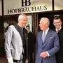 Drei Männer stehen vor dem Münchner Hofbräuhaus, in der Mitte steht König Charles