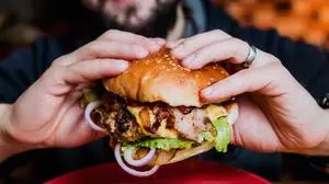 Young man eating a cheeseburger. Restaurant