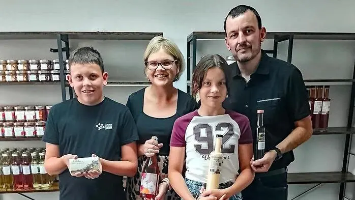 Die Inhaberin mit ihrem Mann, Sohn und Tochter die in die Kamera lachen und Produkte in der Hand halten