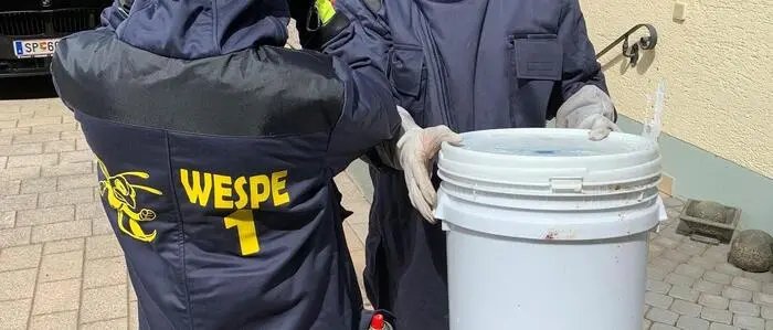Man sieht zwei Feuerwehrleute in Anzügen gegen Wespen