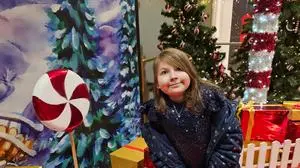 Lina sitzt vor einem Christbaum und Geschenken  | Lina liebte es, anderen eine Freude zu machen