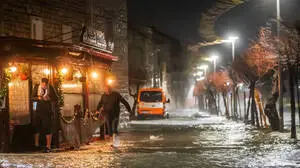 Überschwemmte Straße mit Fußgängern und Fahrzeug