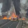 Man sieht Feuerwehrwagen auf einer Autobahn vor einem gewaltigen Feuer und dicken schwarzen Rauchsäulen | Das Feuer und die Rauchschwaden waren nach dem tödlichen Unfall weithin zu sehen