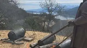 Man sieht einen Mann mit einem brennenden Stab und Milchkannen am Boden