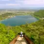 Man sieht eine Frau von hinten und vor ihr Wald- und Seenlandschaft