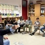 Man sieht einen Mann mit vor Kindern sitzend, alle haben einen Geldschein in der Hand | Andreas Pregl bringt den interessierten Schülern der VS Völkermarkt das Thema Finanzen näher