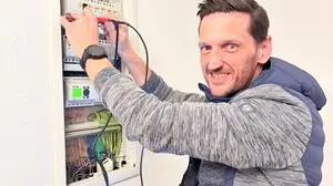 Ein Mann steht bei einem Sicherungskasten