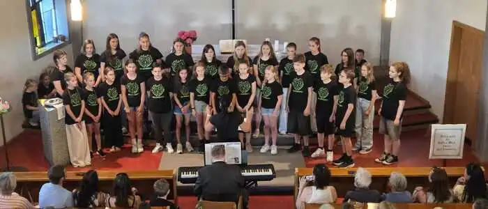 Mehrere Jugendliche und Kinder stehen auf einer Bühne vor einem Publikum