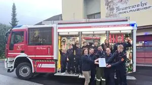 Ein Teil der Jugendfeuerwehr der FF Miklauzhof steht auf einem Löschfahrzeug, im Vordergrund die Jugendbetreuer, die eine Urkunde für die Wahl zur beliebtesten Jugendgruppe entgegennehmen. Im Hintergrund ist das Rüsthaus der FF Miklauzhof | Große Freude über den Bezirkssieg: Kleine Zeitung-Teamleiterin Bettina Friedl überreicht die Urkunde an Tobias Neuper, Markus Klanschek, Markus Hobel-Podrecnik und Alexander Marchsteiner von der FF Miklauzhof. Im Hintergrund jubelt ein Teil der Jugendfeuerwehr-Truppe am Fahrzeug