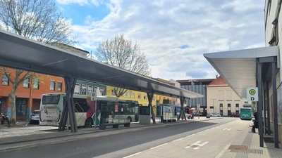 Man sieht einen geparkten Bus und eine überdachte Bushaltestelle