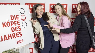 Drei junge Frauen zeigen lachend auf das „Köpfe des Jahres“-Schild