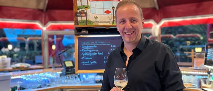 Pierre Fritzl steht mit einem Glas in der Hand mitten im Café