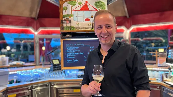 Pierre Fritzl steht mit einem Glas in der Hand mitten im Café