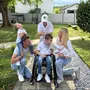 Vier Kinder mit ihren Eltern, eines davon sitzt im Rollstuhl und alle tragen Jeans mit einem weißen Oberteil