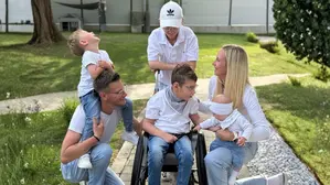 Vier Kinder mit ihren Eltern, eines davon sitzt im Rollstuhl und alle tragen Jeans mit einem weißen Oberteil