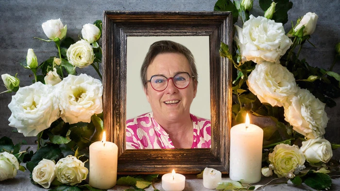 Die Verstorbene ist in einem Bilderrahmen, umgeben von Kerzen und Blumen zu sehen
