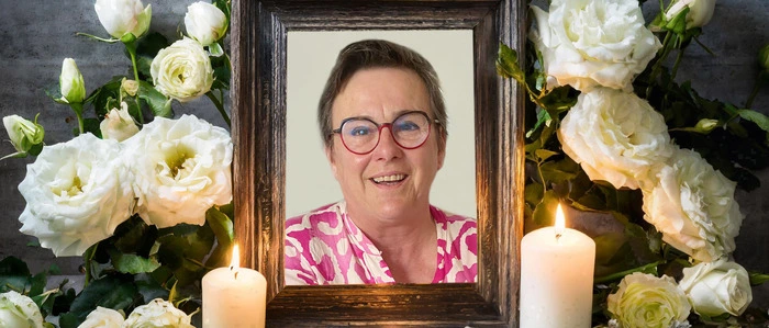 Die Verstorbene ist in einem Bilderrahmen, umgeben von Kerzen und Blumen zu sehen
