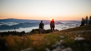 Sonnenaufgang mit Bergen im Hintergrund und zwei Wanderern