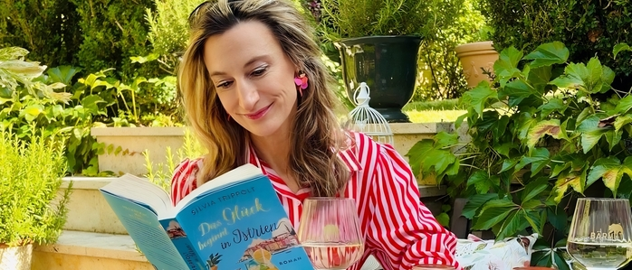 Eine Frau sitzt an einem Tisch und liest ein Buch
