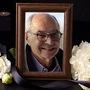 Ein Bild eines Mannes in einem Bilderrahmen, umgeben von Blumen