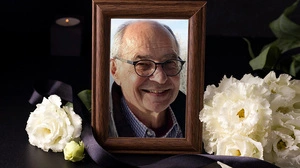 Ein Bild eines Mannes in einem Bilderrahmen, umgeben von Blumen