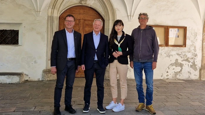 Vier Personen stehen vor dem Eingang einer Kirche
