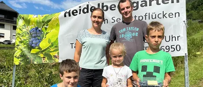 Eine Familie steht in einem Heidelbeerfeld