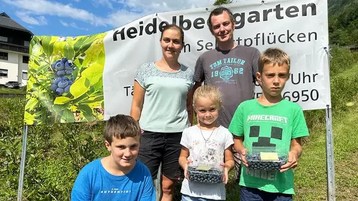 Eine Familie steht in einem Heidelbeerfeld