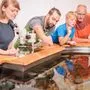 Vier Personen lehnen über einem Wasserbecken