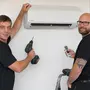Zwei Männer installieren eine Klimaanlage