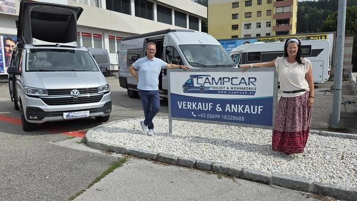 Ein Mann und eine Frau stehen bei einem Plakat nahe einem Geschäft