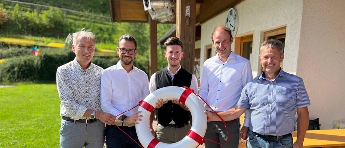 Fünf Männer halten vor einem Bad einen Rettungsring