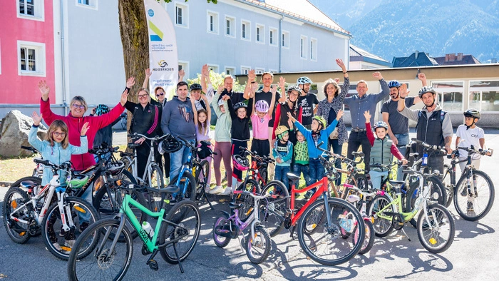 Kinder stehen mit ihren Rädern auf einem Parkplatz