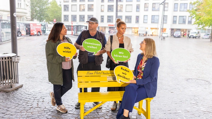 Vier Menschen haben sich um eine Bank versammelt
