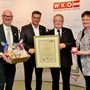 Vier Personen mit Urkunden und Geschenken