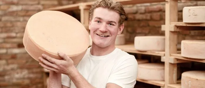 Ein Mann steht vor einem Regal voller Käse