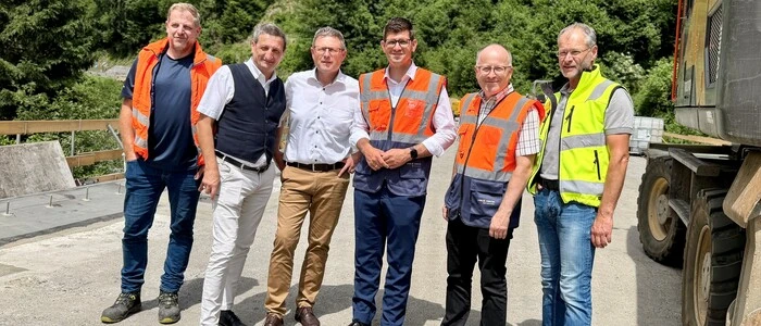Sechs Männer stehen bei einer Baustelle
