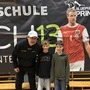 Drei Personen vor einem Plakat | Kurt Gomig mit zwei jungen Spielern