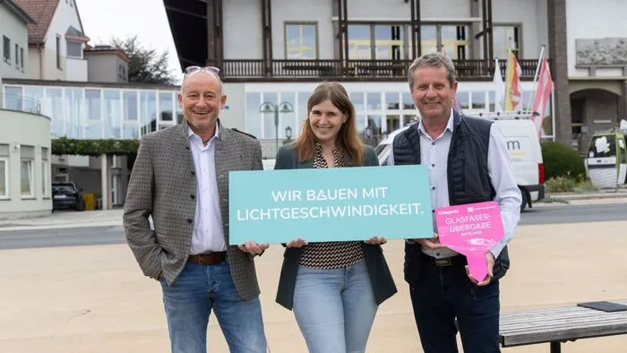 Drei Personen mit einem Plakat