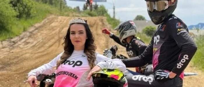 Eine junge Frau mit einem Motorradfahrer auf einer Rennstrecke