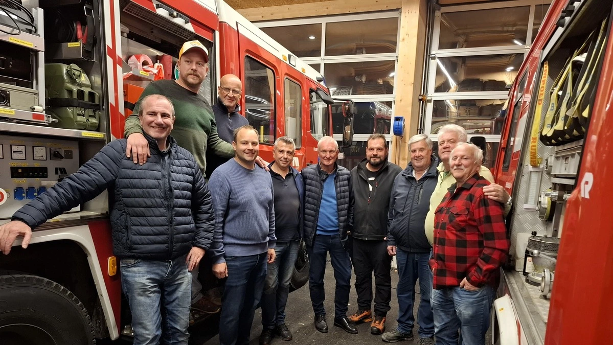 Zehn Feuerwehrleute zwischen zwei Feuerwehrautos | Die Feuerwehrmänner besprachen unter anderem einen Transfer von Tanklöschfahrzeugen
