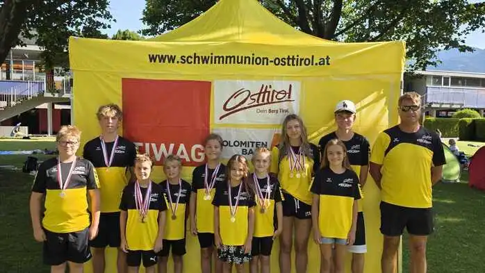 Junge Schwimmer stehen vor einem Zelt