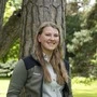 Eine junge Frau steht vor einem Baum