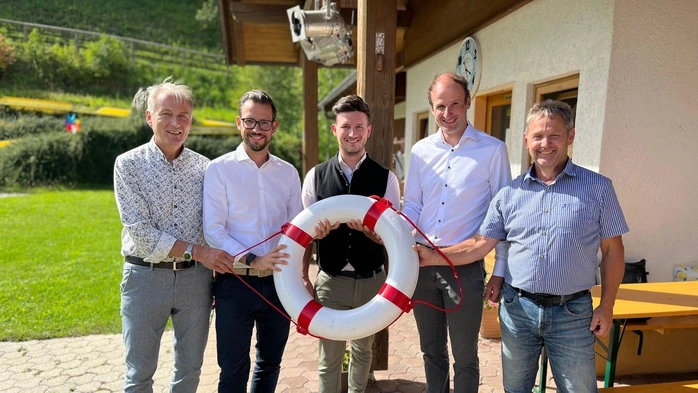 Fünf Männer halten vor einem Bad einen Rettungsring