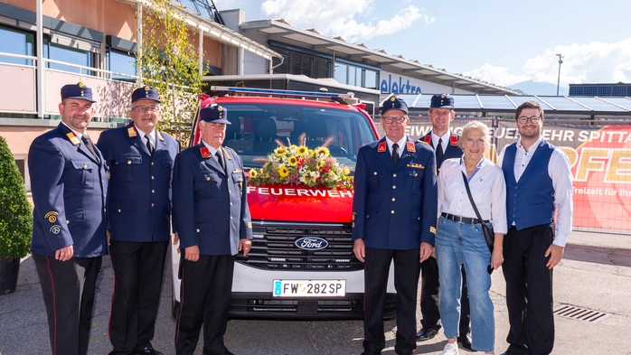 Feuerwehrleute stehen um ein Feuerwehrauto