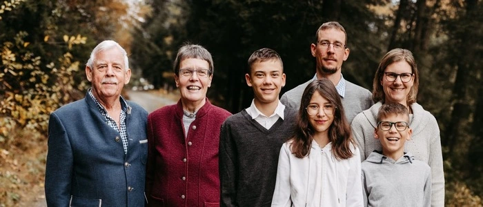 Sieben Familienmitglieder stehen in einem Wald