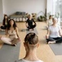 Mehrere Menschen sitzen auf Sportmatten und machen zusammen Yoga
