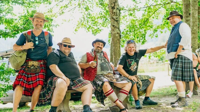 Männer in Tracht sitzen in einem Wald