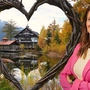 Eine Frau steht neben einem großen Herzen und vor einem Teich und Hotel