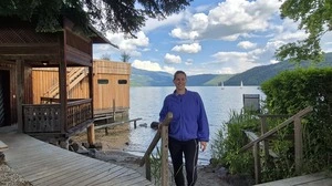 Eine Frau steht auf einer Holzstiege vor einem See